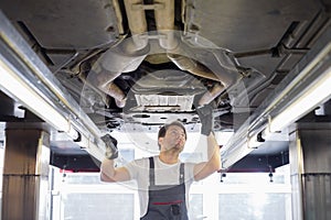 Mid adult male repair worker repairing car in workshop