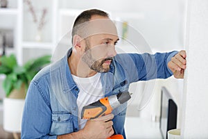 mid-adult man drilling hole in wall photo