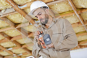 mid-adult man drilling hole in wall