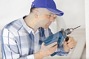 mid-adult man drilling hole in wall