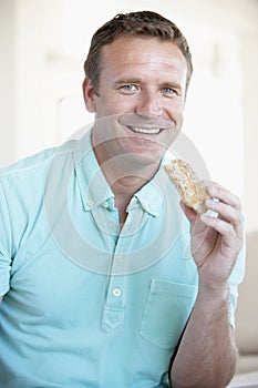Mid Adult Man Eating Brown Bread Roll