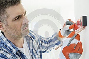 Mid-adult man marking on wall with level