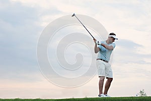 Mid-adult man playing golf against sky