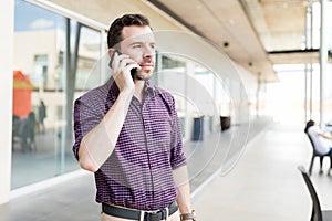 Man Taking Call On Smartphone In Shopping Mall