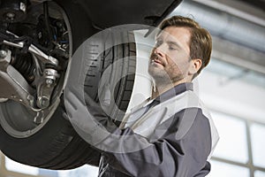 Mid adult technician adjusting car's tire in workshop