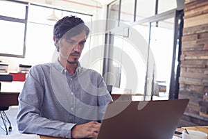 Mid-adult white man working in an office using laptop, close up