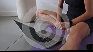 Mid adult woman doing yoga with tutorial on the laptop