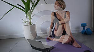 Mid adult woman doing yoga with tutorial on the laptop