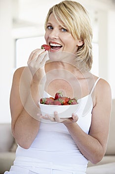 Mid Adult Woman Eating A Bowl Of Strawberries