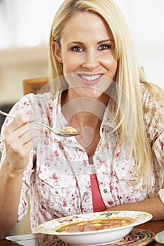 Mid Adult Woman Eating Soup, Smiling At The Camera