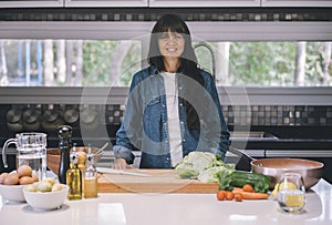 Mid adult woman housewife preparing meal while looking at camera
