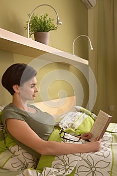 Mid-adult woman reading in bed