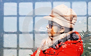 Mid Adult Woman in red winter clothing wearing hat and sunglasses. Head and Shoulder Shot. Side face. Close up. Looking through