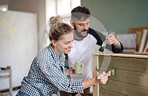Mid adults couple painting furniture indoors at home, relocation and diy concept.