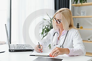 Mid age female doctor writing prescription