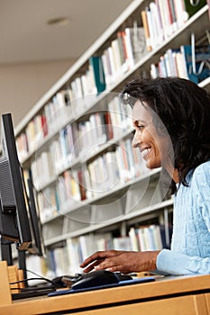 Mid age woman working on computer in library