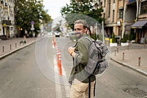 Mid aged, handsome man with backpack, ready to embark on journey and explore old city of Europe. Adventure and travel