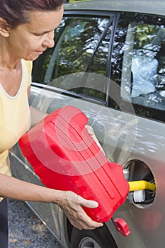 Mid aged woman adding fuel in car