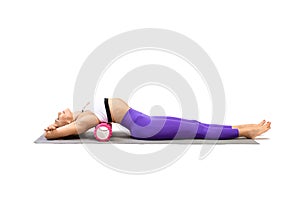 Mid back extension. Attractive fit woman lying on back and using pilates roller to stretch and relax her thoracic