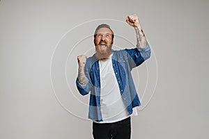 Mid bearded man in denim shirt screaming and gesturing in excitement