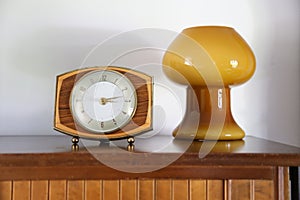 Mid century decor. Vintage or retro clock in shape focus on a sideboard with a background retro blown glass mushroom lamp