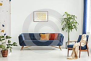 Mid-century modern chair with a blanket and a large sofa with colorful cushions in a spacious living room interior with green plan