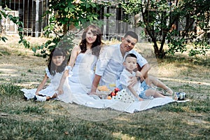 Mid distance portrait of an asian family in white clothes having picnic in park