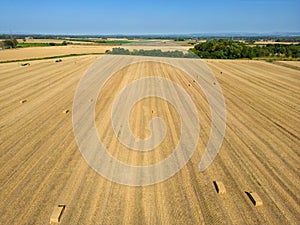 Mid level aspect view over a wheat field with bales of straw ready for collection in the English countryside