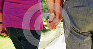 Mid section of active senior couple walking hand in hand in the garden of nursing home 4k