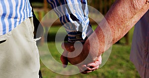 Mid section of active senior couple walking hand in hand in the garden of nursing home 4k