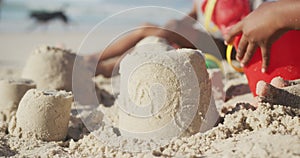 Mid section of african american girl playing with sand on the beach