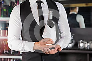 Mid section of bartender holding a wine bottle
