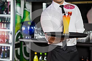 Mid section of bartender serving cocktail