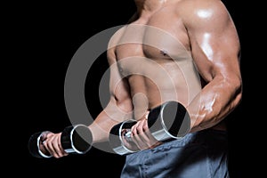 Mid section of a bodybuilder with dumbbells