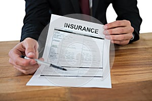 Mid section of businessman sitting at desk holding insurance contract