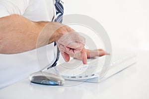 Mid section of businessman using computer keyboard