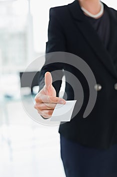 Mid section of businesswoman handing business card