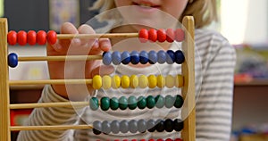 Mid section of Caucasian schoolgirl learning mathematics with abacus in the classroom 4k