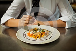 Mid section of chef garnishing pasta dish with olive