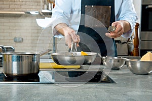 Mid section of chef preparing food in the kitchen of a restaurant