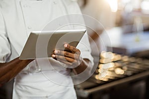 Mid section of chef using digital tablet
