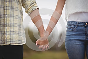 Mid section of couple holding hands at farm