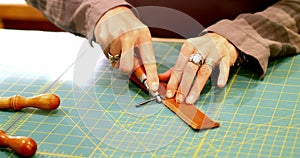 Mid-section of craftswoman cutting leather