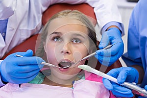 Mid section of dentist and nurse examining a young patient with tools
