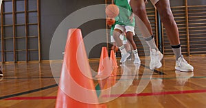 Mid section of diverse female basketball team and coach practice dribbling ball