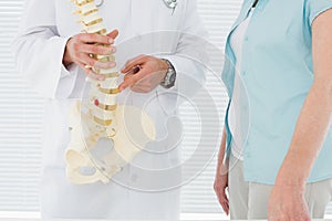 Mid section of a doctor explaining the spine to patient