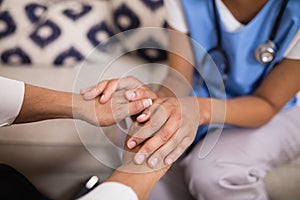 Mid section of doctor touching patient hands