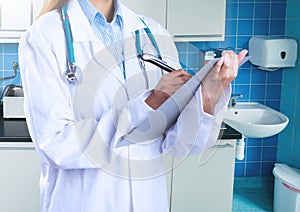 Mid section of female doctor writing on clipboard