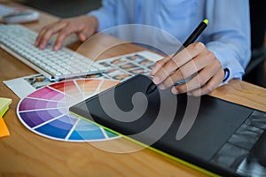 Mid section of female graphic designer using graphics tablet at desk