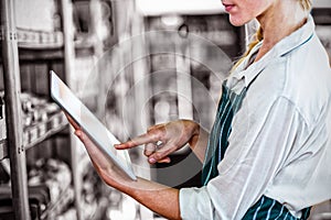 Female staff using digital tablet in supermarket